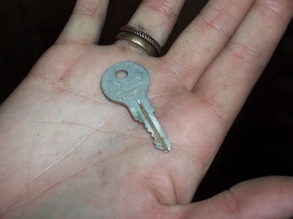 Grauer Schlüssel in der Handfläche der Person