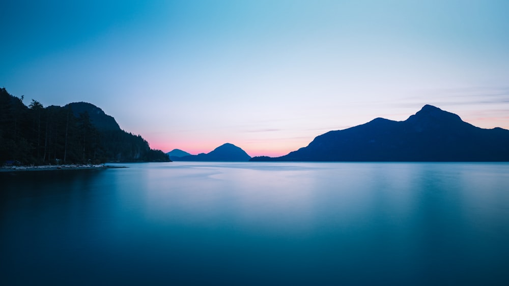 silhouette photo of mountain range near body of water