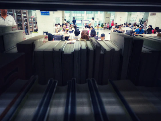 A diverse group of learners happily engaging with books and laptops in a bright, green-themed study space.