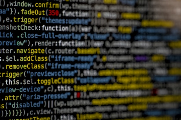 Lines of highlighted computer code appear on a dark screen, with syntax elements in various colors including yellow, blue, white, and purple.