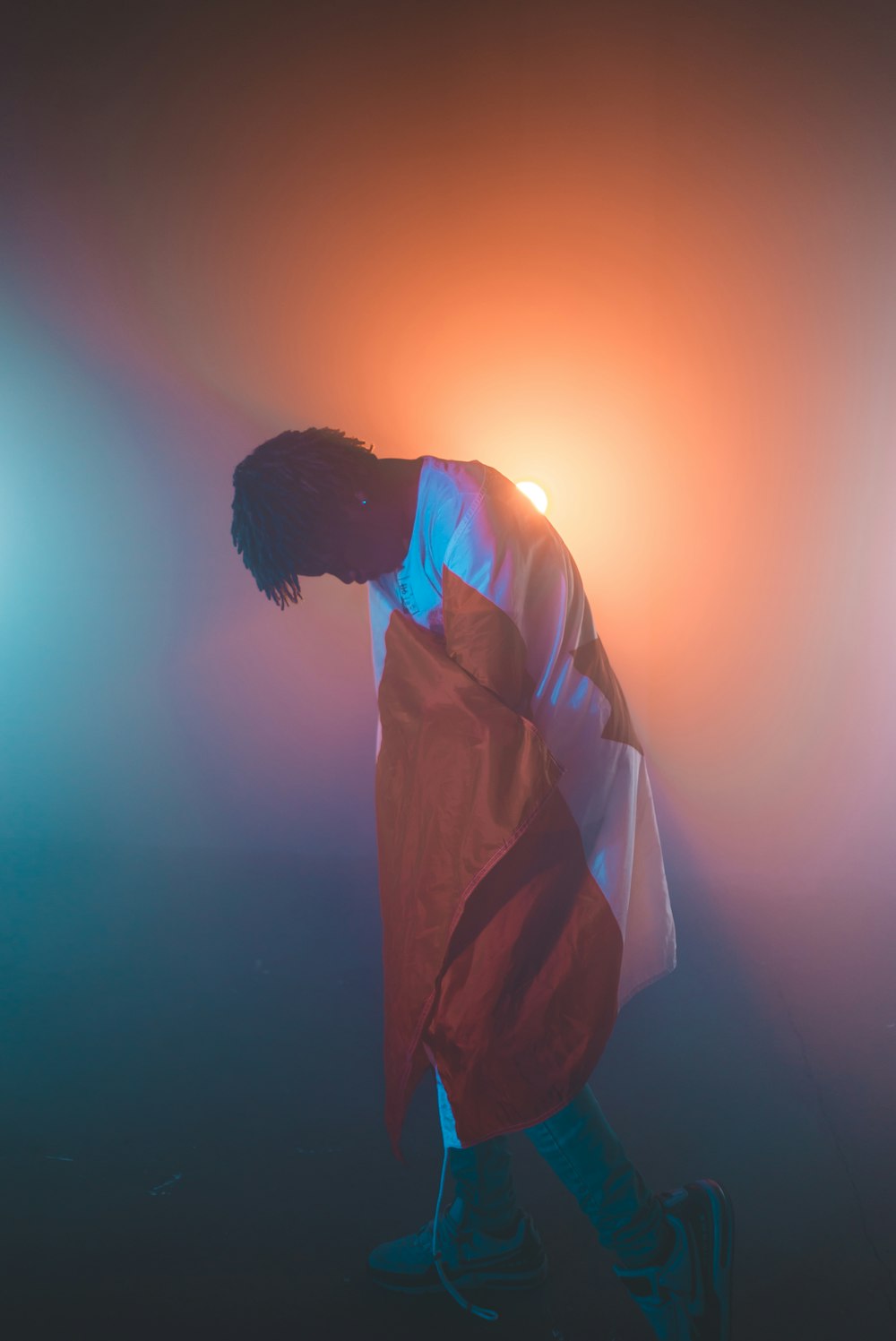 man wearing white and orange long-sleeved shirt standing near orange light