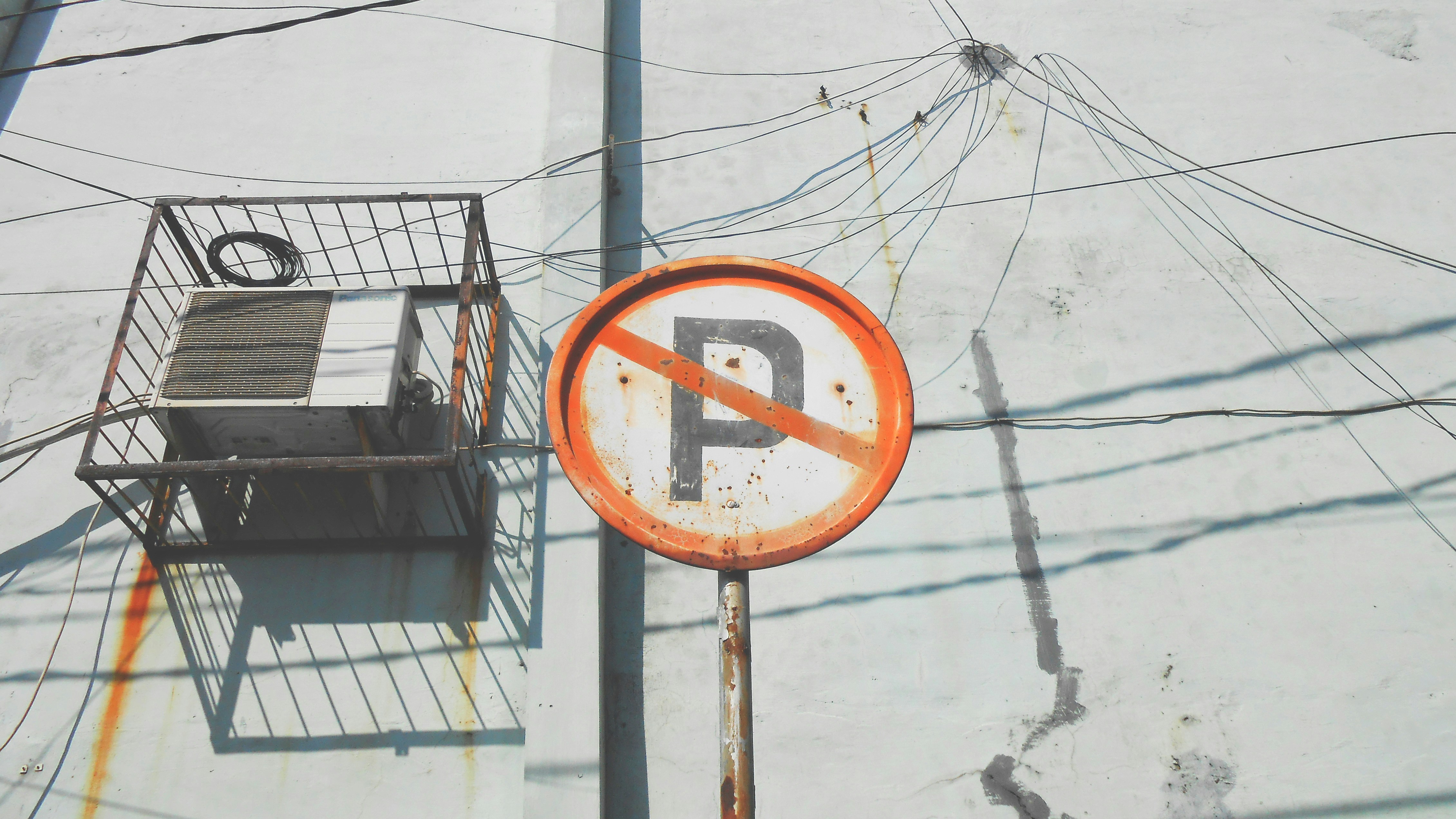 Rusty Caged Air Conditioner Behind No Parking Sign