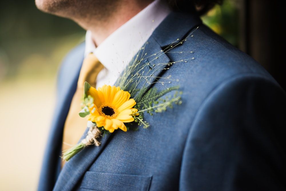man in blue suit jacket with yellow clipped flower