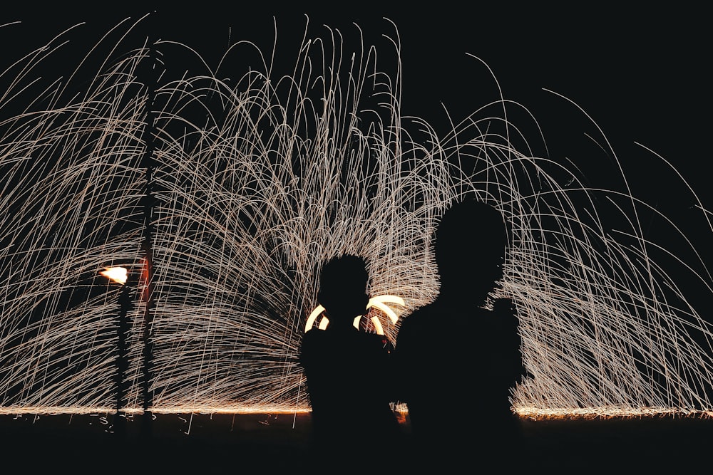 man and woman kissing in front of fireworks display during night time