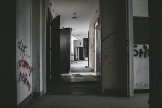 A grainy, dimly lit scene of an abandoned asylum corridor.