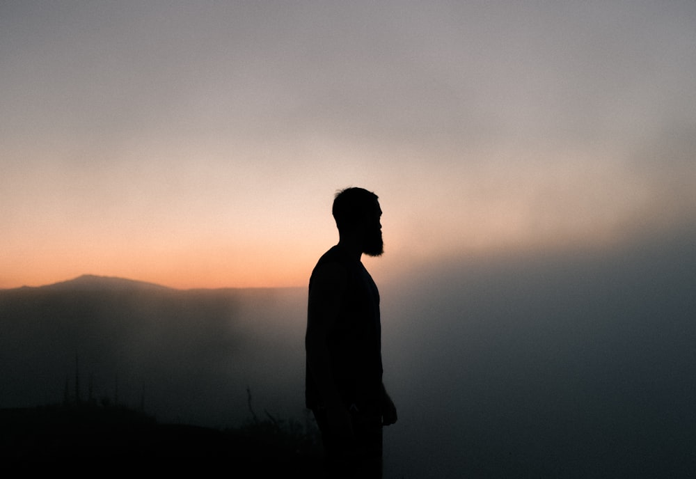 silhouette dell'uomo circondato da nebbia durante l'ora d'oro