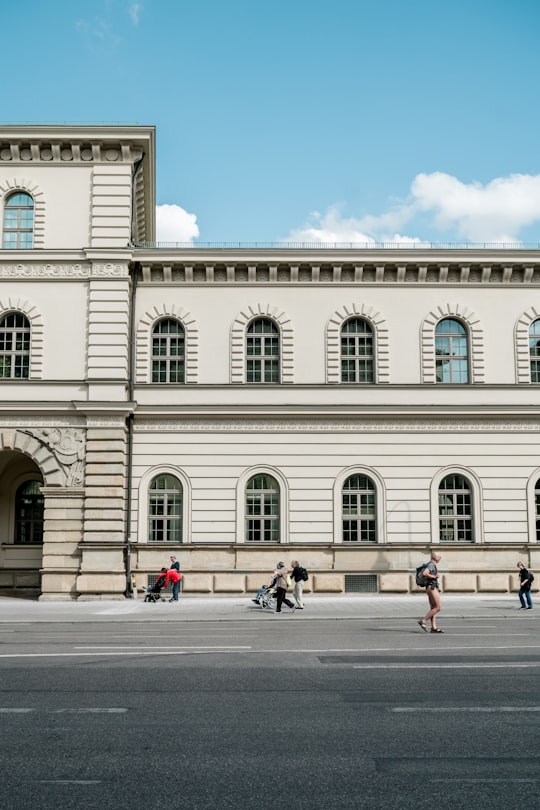 man carrying backpack walking along the road beside concrete building in Universität Germany