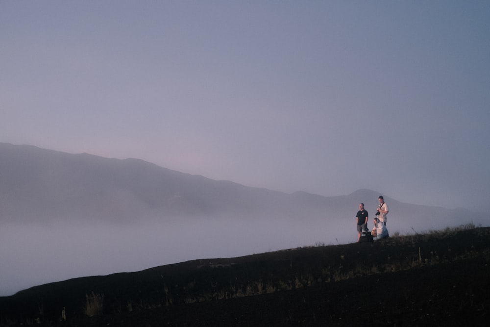 group of people standing on green grass hill