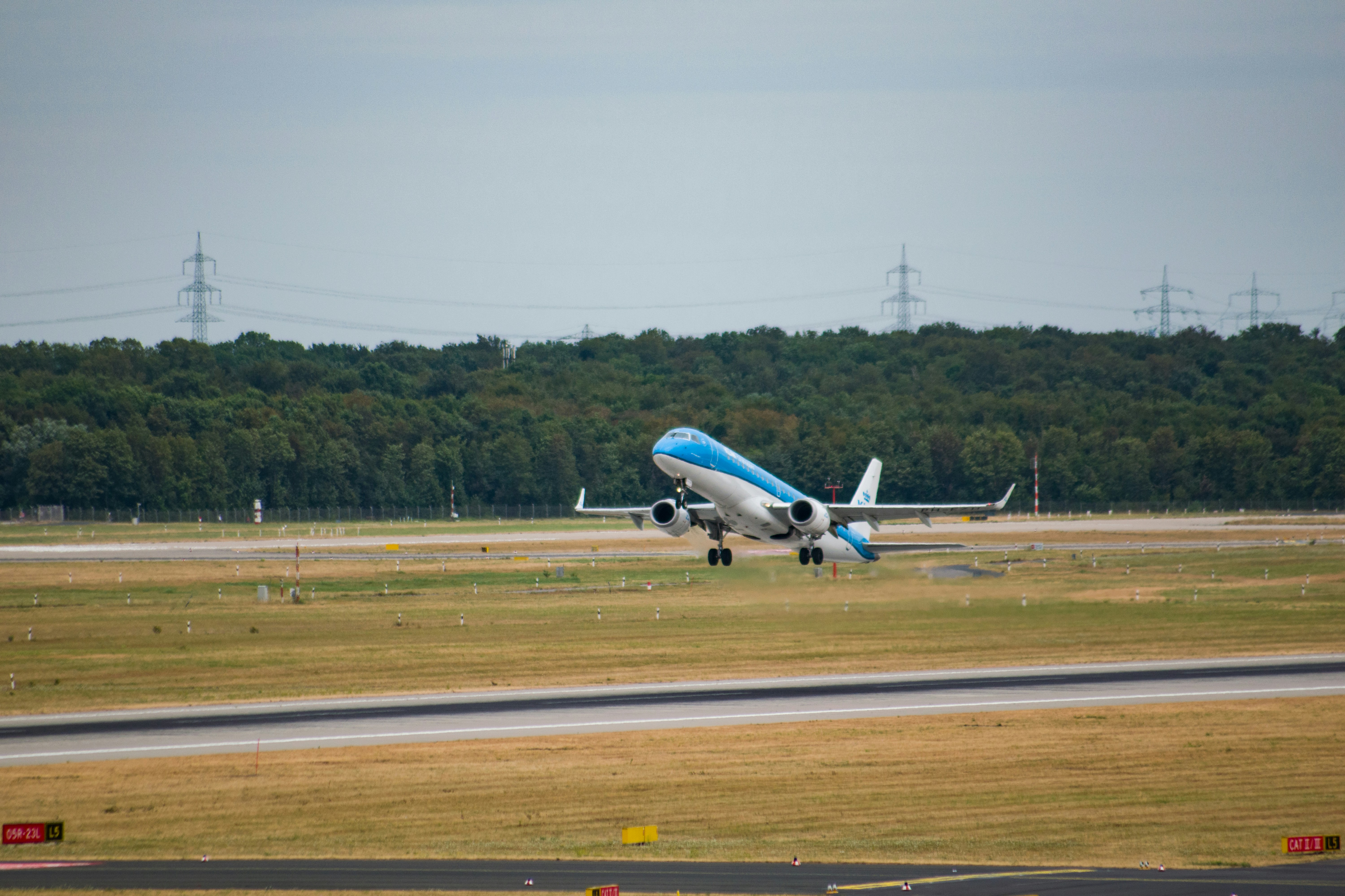 a blue and white plane taking off from an airport runway, 