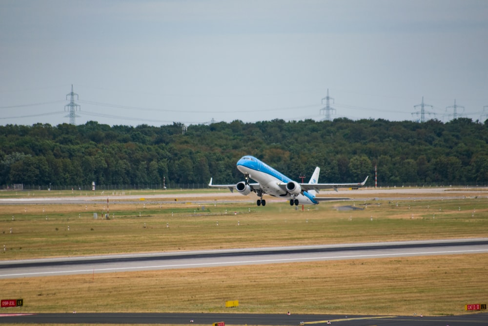 a blue and white plane taking off from an airport runway