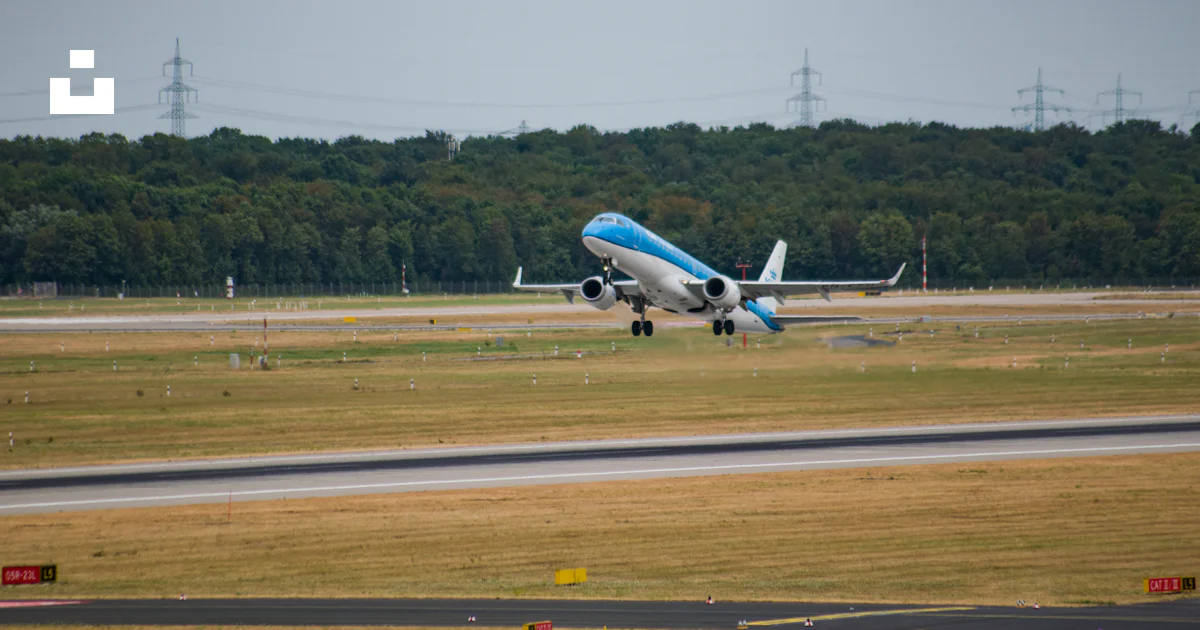 A blue and white plane taking off from an airport runway photo – Free ...