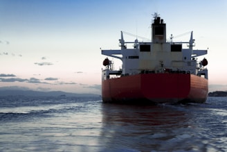 A cargo ship navigating through calm waters at sunset.