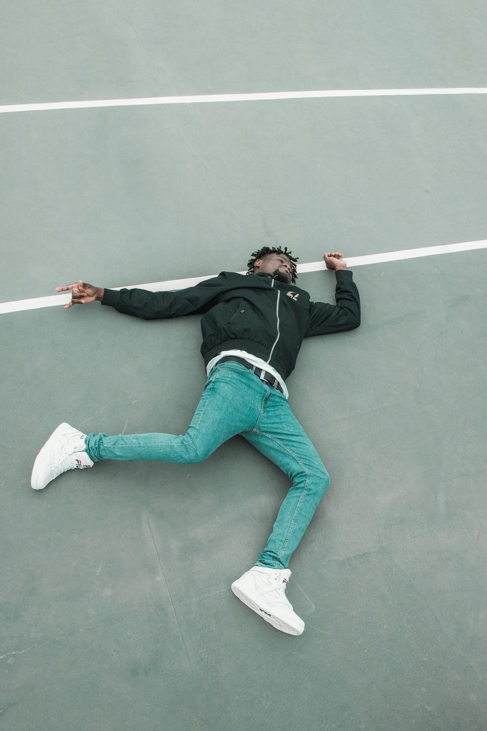 man lying on gray white lined concrete floor