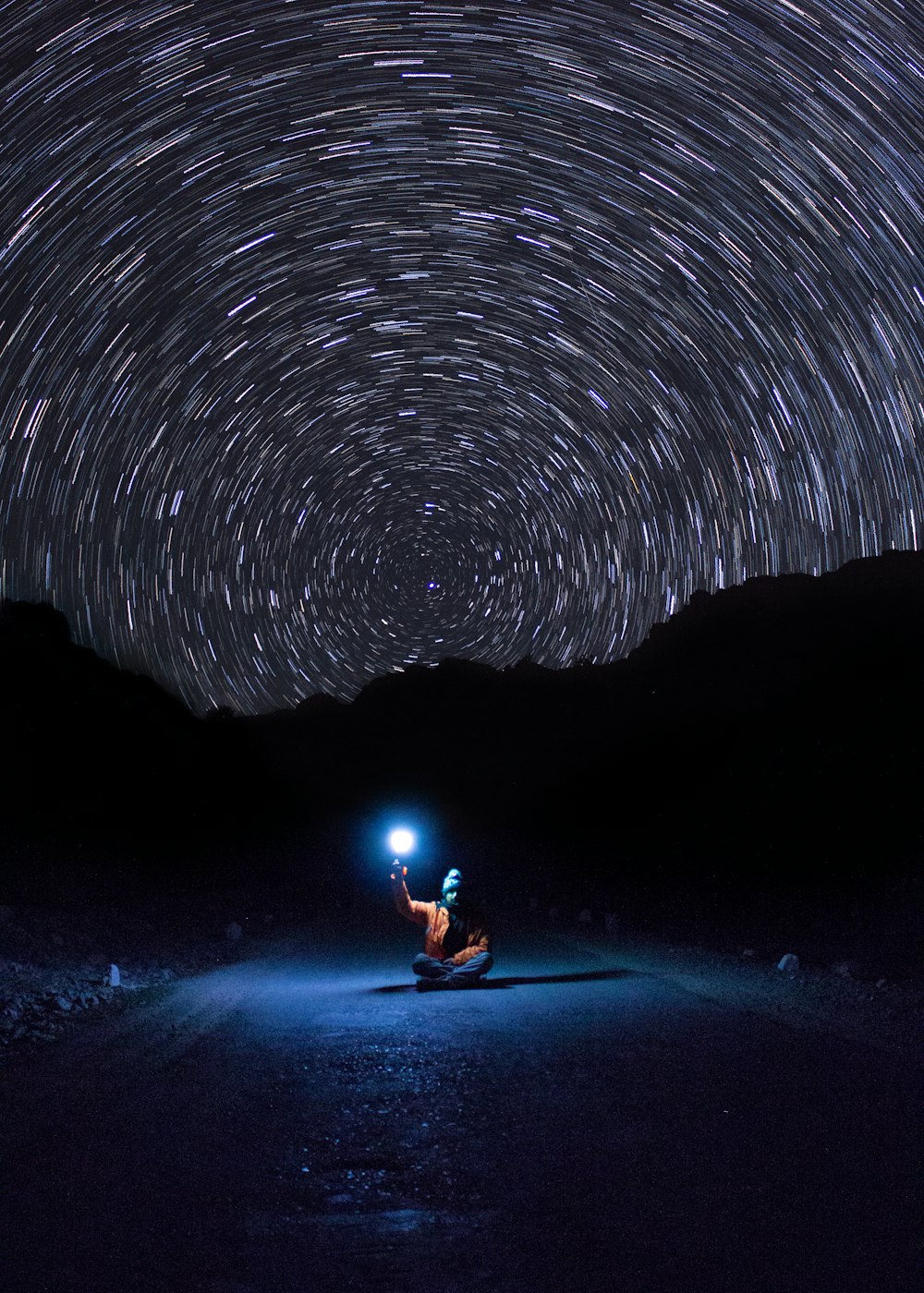 photo of person sitting on pave road holding light