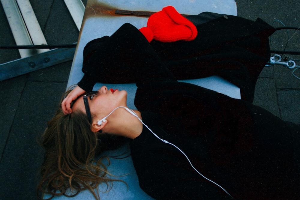 woman in black shirt lying on blue surface