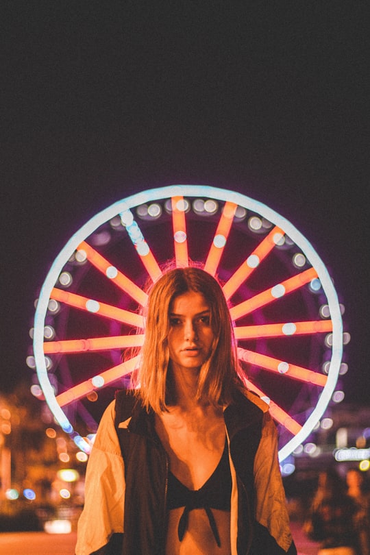 woman standing in front of lighted Ferris wheel at nighttime in Cannes France