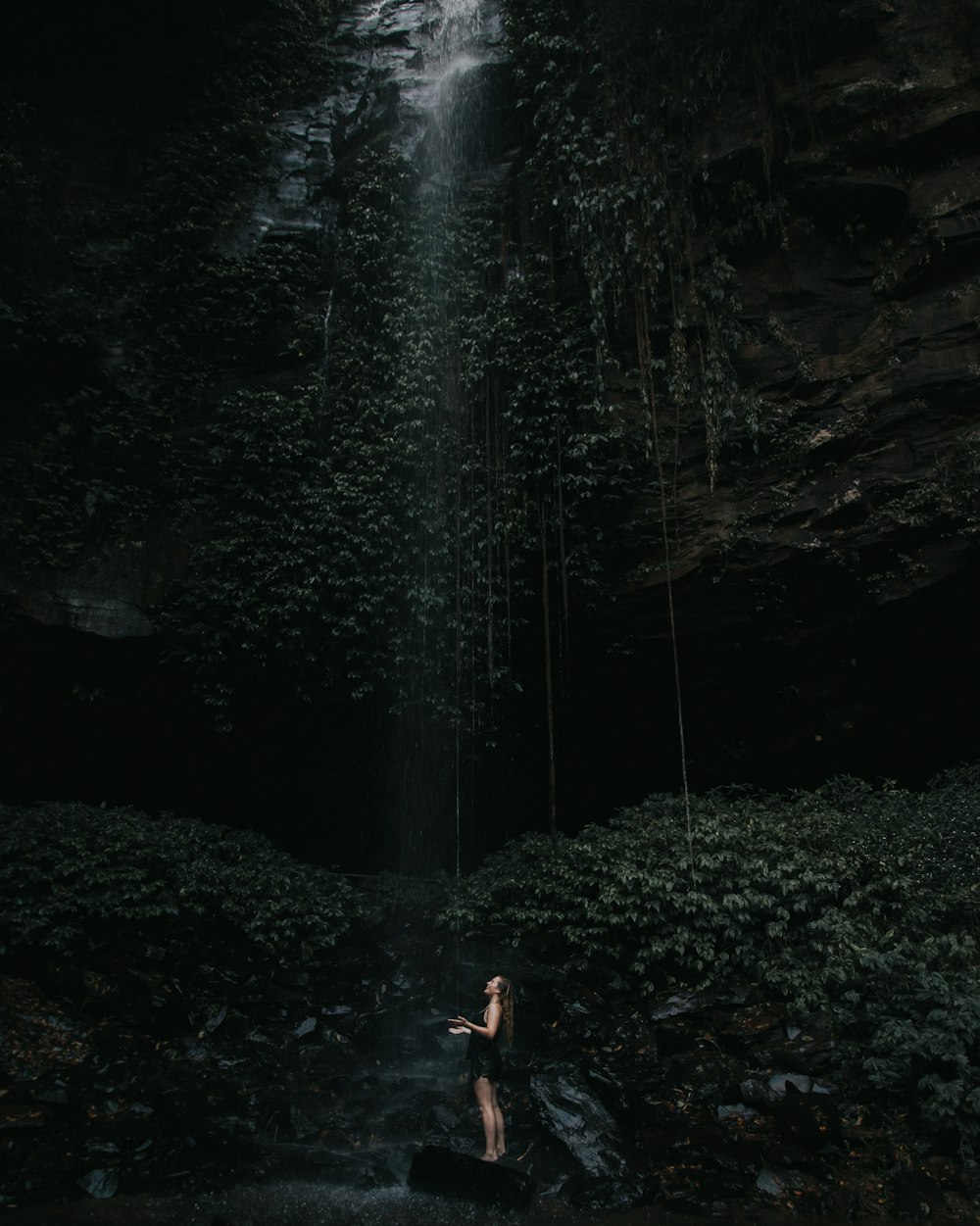 mulher em pé sob cachoeiras durante o dia