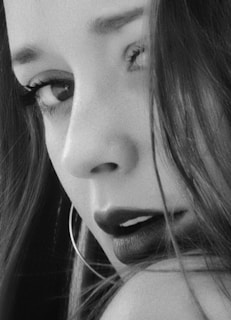 Close-up black and white image capturing delicate details of a young model’s face with soft contrast