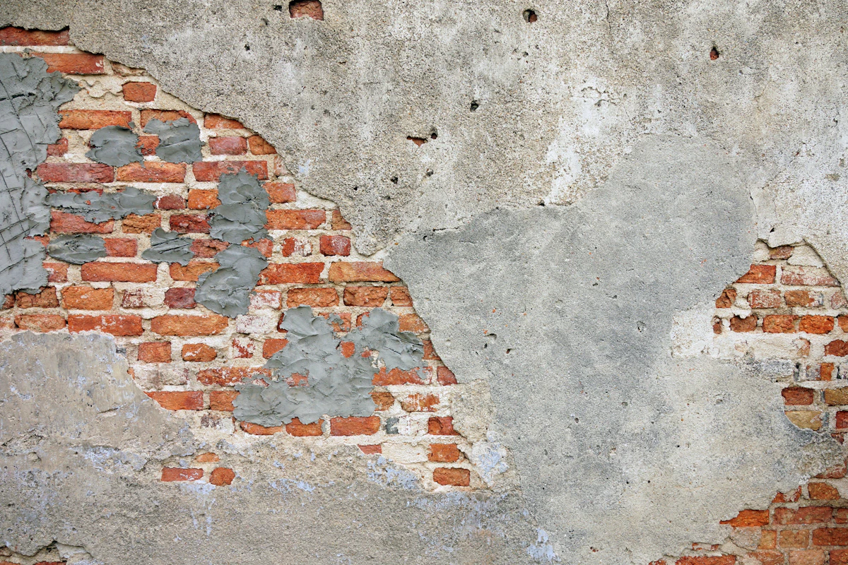 Crumbling brick wall with damaged plaster before repointing