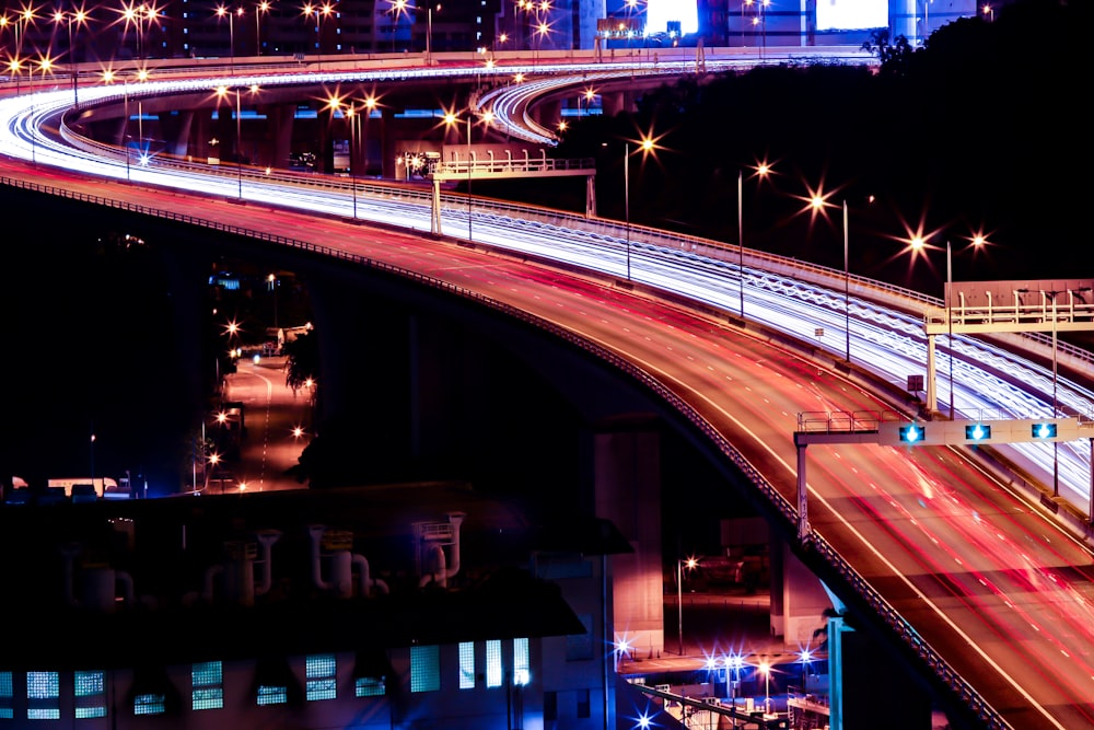Photographie en accéléré de la route avec des voitures près du bâtiment la nuit