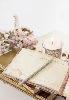 Agenda ouvert et posé à côté d'une bougie et des fleurs dans des tons doux