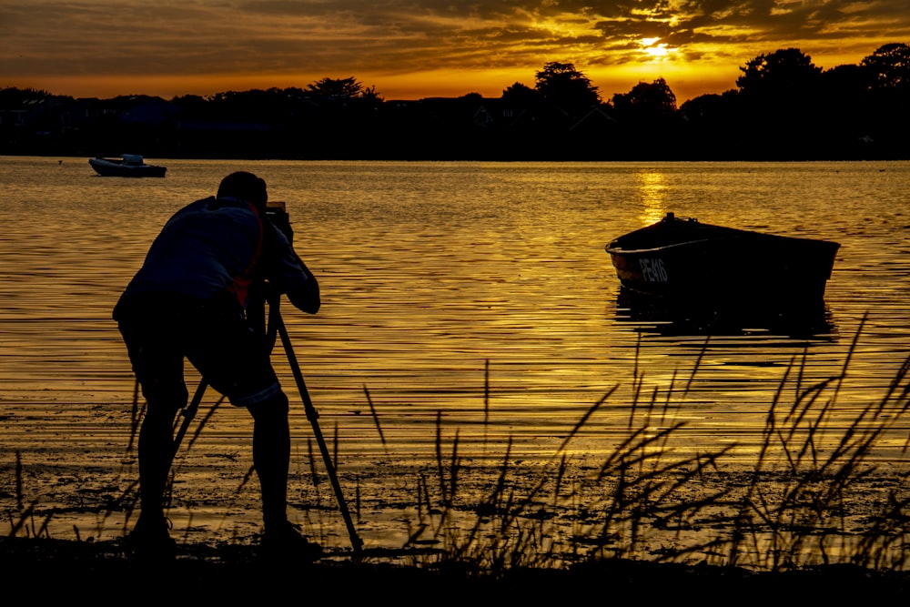 Silhouettenfotografie eines Mannes, der auf einem Boot fotografiert