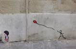 A vibrant Banksy mural showing a girl releasing a heart-shaped balloon on a city wall.