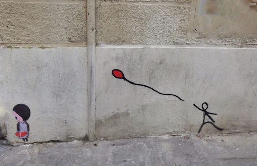 A vibrant Banksy mural showing a girl releasing a heart-shaped balloon on a city wall.