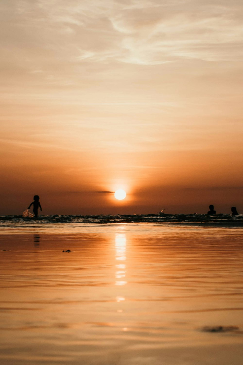 Fotografia de silhueta de duas pessoas no corpo de água durante o pôr do sol