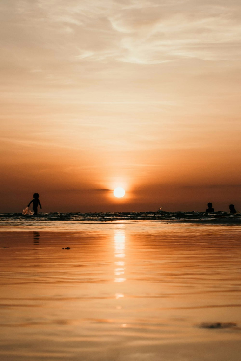 Fotografía de la silueta de dos personas en el cuerpo de agua durante la puesta del sol