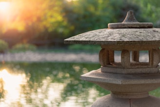 a stone lantern sitting on top of a rock near a body of water