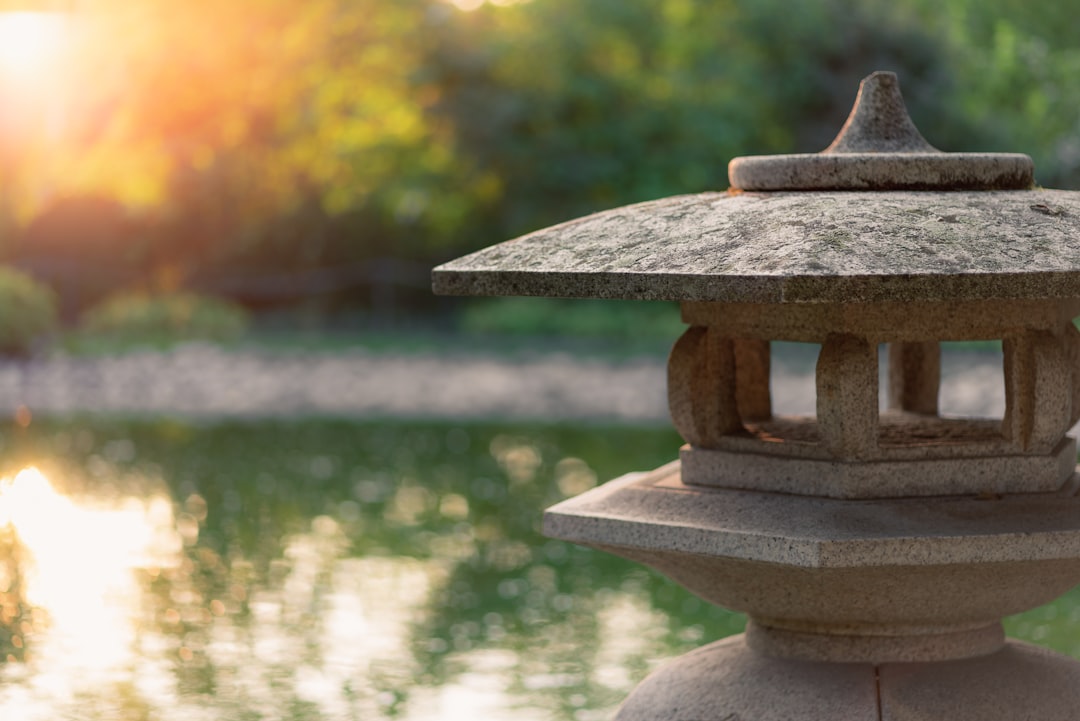 a stone lantern sitting on top of a rock near a body of water, Japanese Garden