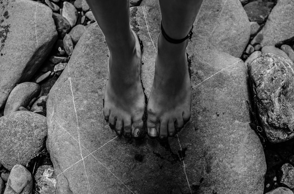 Photographie en niveaux de gris d’une personne debout sur un rocher