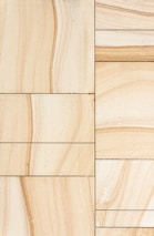 Rectangular sandstone tiles with natural beige and tan veining are arranged in a grid pattern. The tiles exhibit subtle variations in texture and color, creating a harmonious natural design.