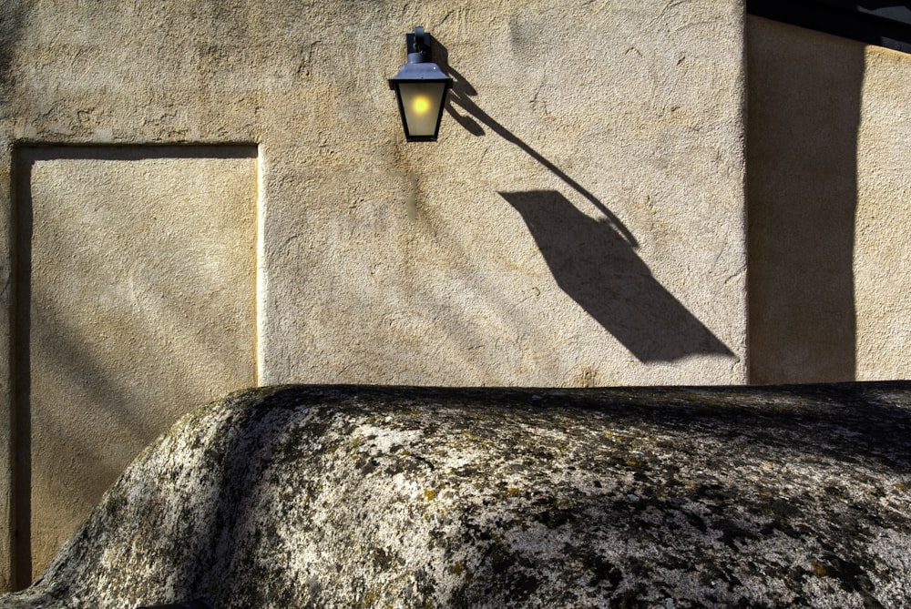 turned-on black outdoor sconce on wall at daytime