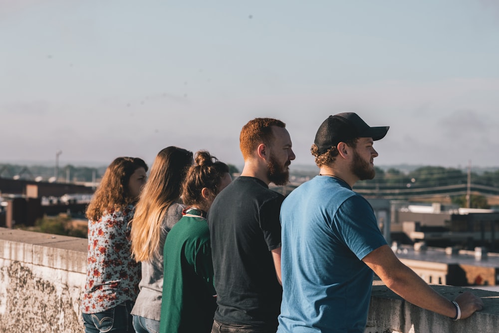 four people leaning on concrete rails