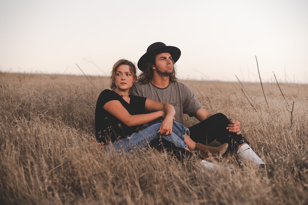 woman and man sitting on wheat field