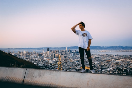 A thoughtful leader standing by a window overlooking a city skyline at dusk.