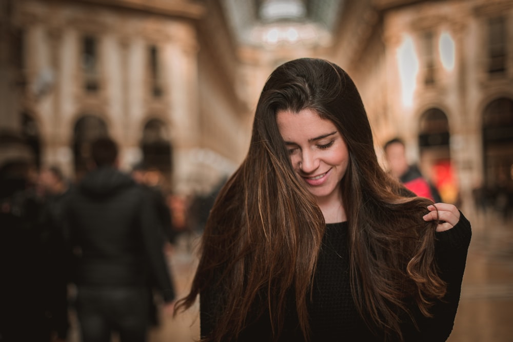 mujer sonriente sosteniendo su cabello mirando en el suelo