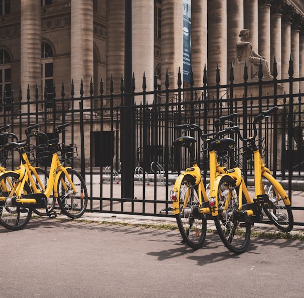 yellow bicycles beside black fence