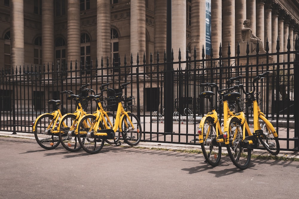 Vélos jaunes à côté de la clôture noire