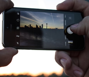A candid shot of a photographer capturing a sunset over a city skyline.