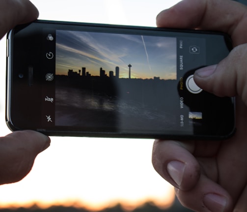 A candid shot of a photographer capturing a sunset over a city skyline.