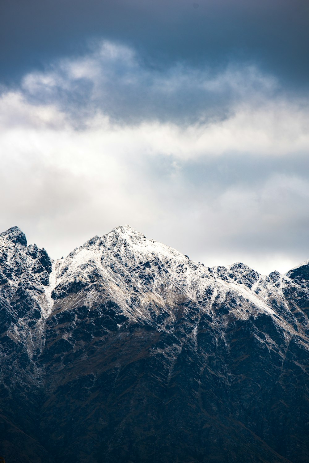snow-capped mountain below cloudy sky