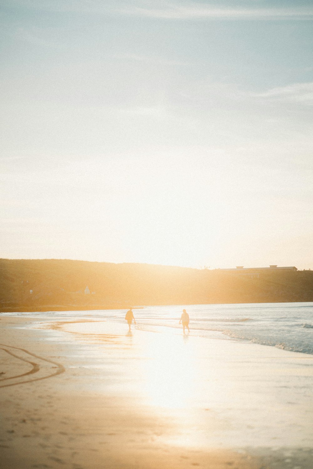 zwei Personen zu Fuß am Meeresufer zur goldenen Stunde