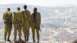 three men and one woman soldiers standing on rock during daytime