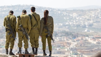three men and one woman soldiers standing on rock during daytime
