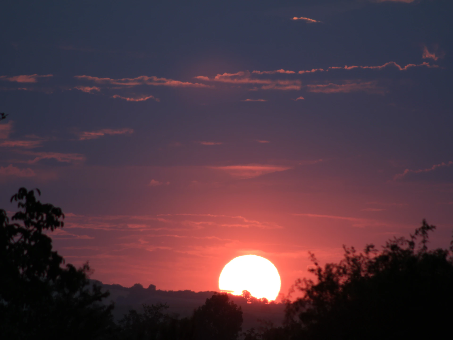 A vibrant sunset casting warm colors over the cenote, creating a tranquil atmosphere.