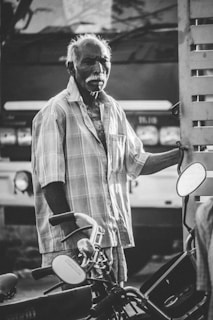 grayscale photography of a man near motorcycles