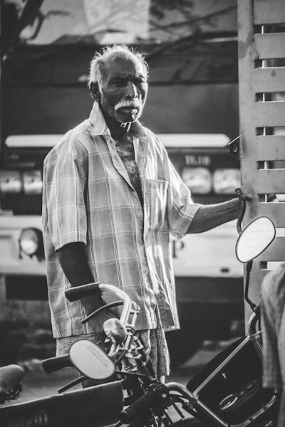 grayscale photography of a man near motorcycles